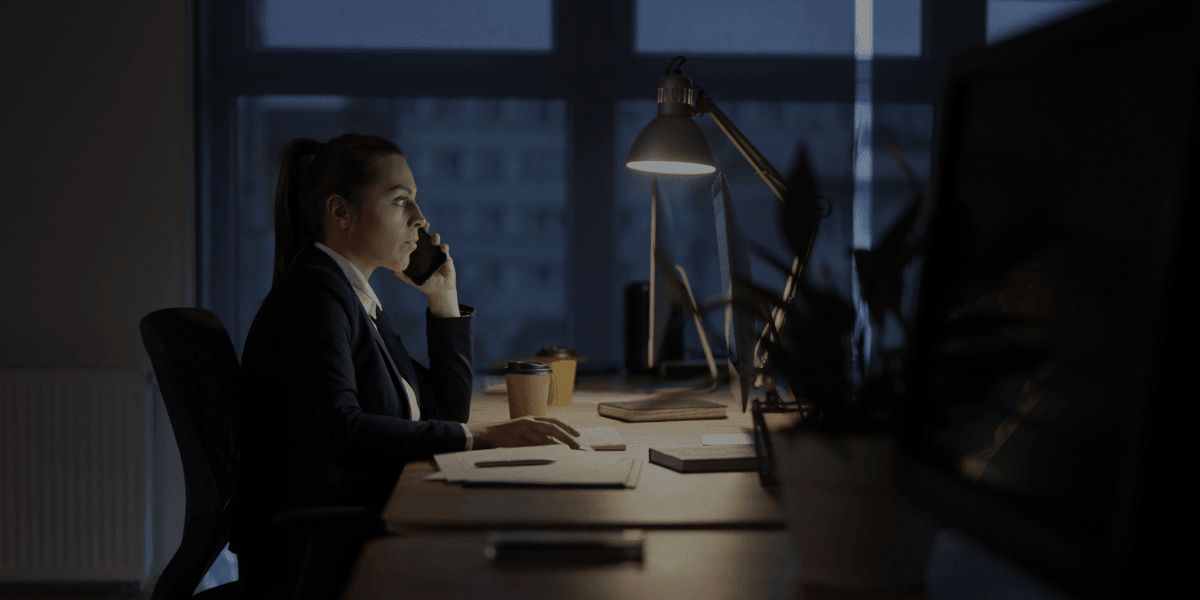 Business professional working late at a desk while talking on the phone in an office.