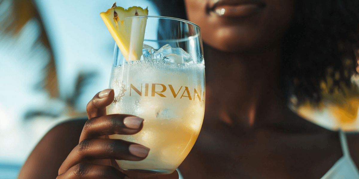 “Woman holding branded Nirvana cocktail, showcasing the company’s premium wellness-focused RTD product and luxury, refreshing lifestyle experience in a tropical setting.”